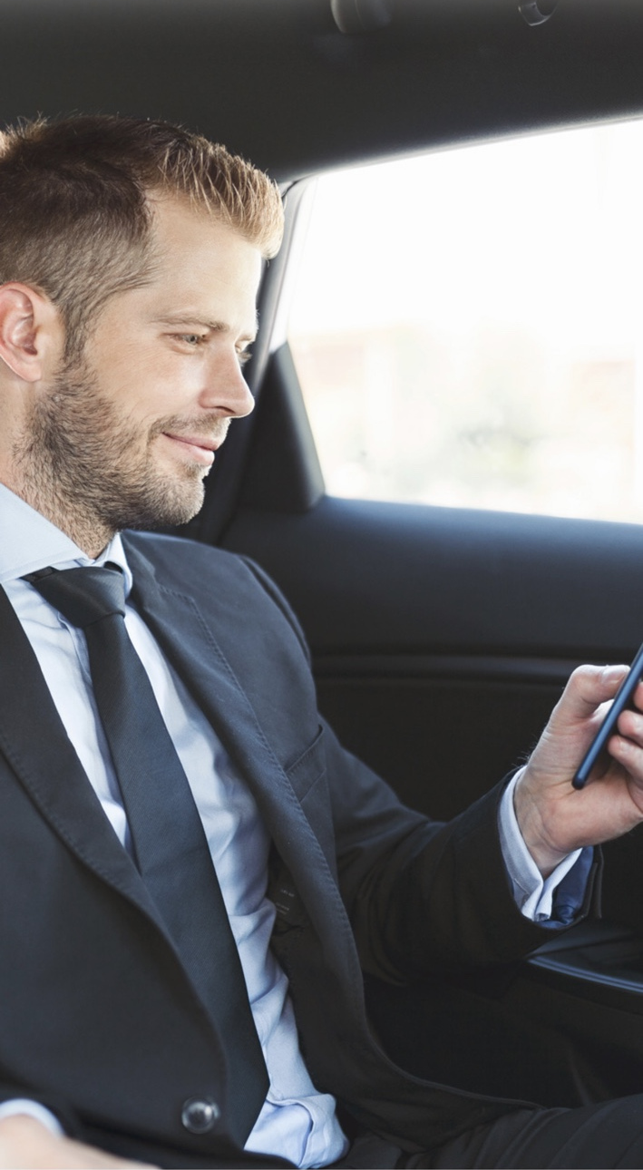 Executive passenger using a smartphone during chauffeured transportation